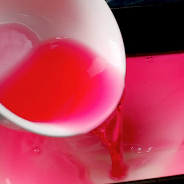 Jello mixture being poured to make layers in rainbow jello.