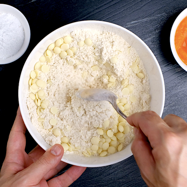 Dry ingredients being mixed with white chocolate chips to make pumpkin scones.