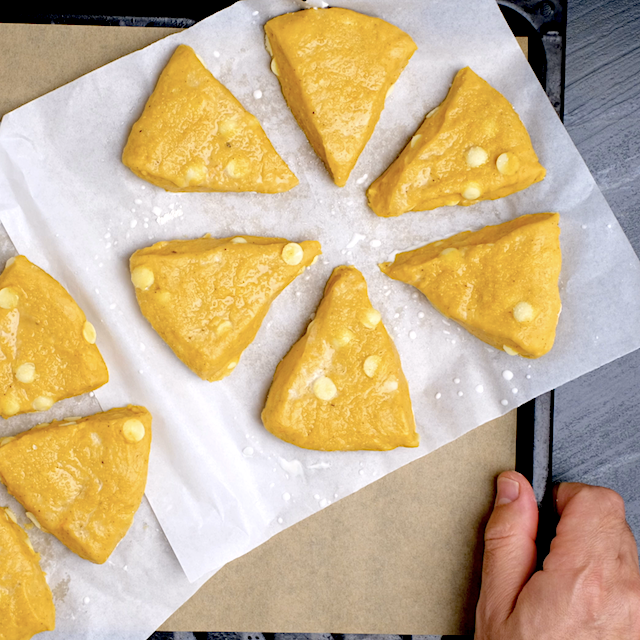 Pumpkin scone wedges on a baking sheet, ready to be baked.