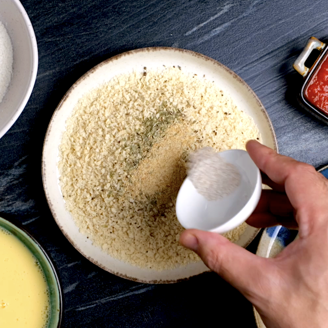 Spices being mixed into Panko breadcrumbs to make homemade mozzarella sticks.