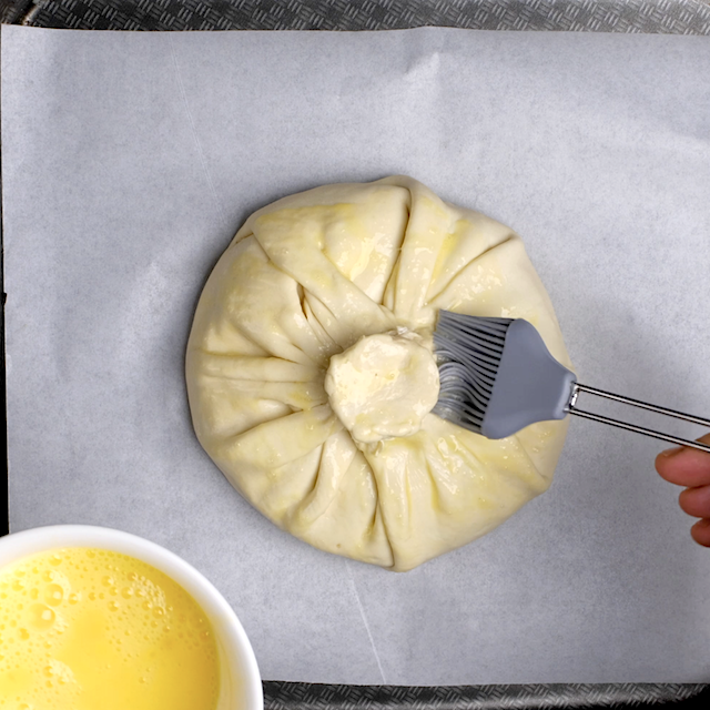 Egg wash being added to brie en croute before baking.