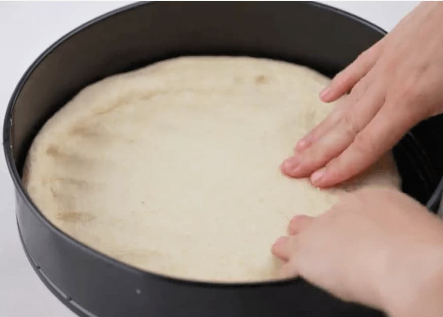 Putting the dough in the pan with my hands.