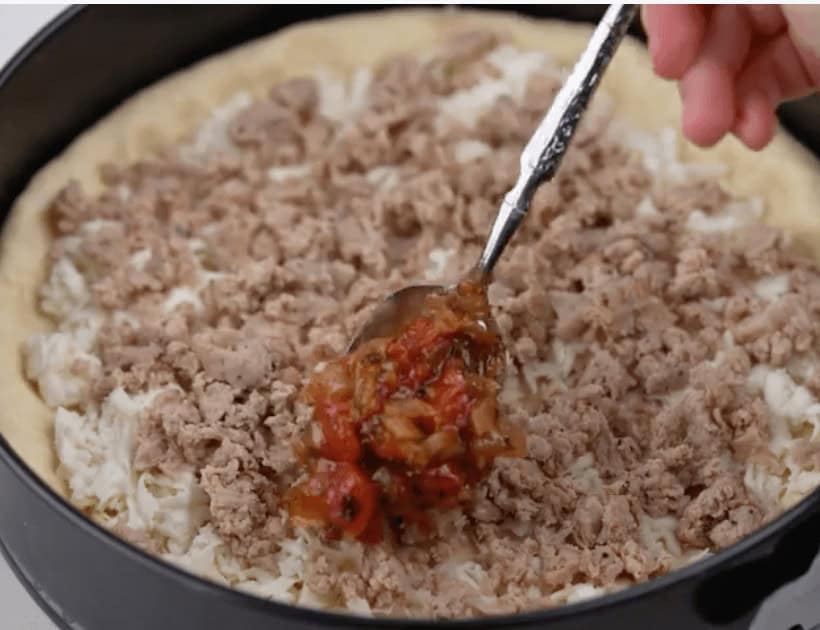 Adding the toppings to the pizza dough.