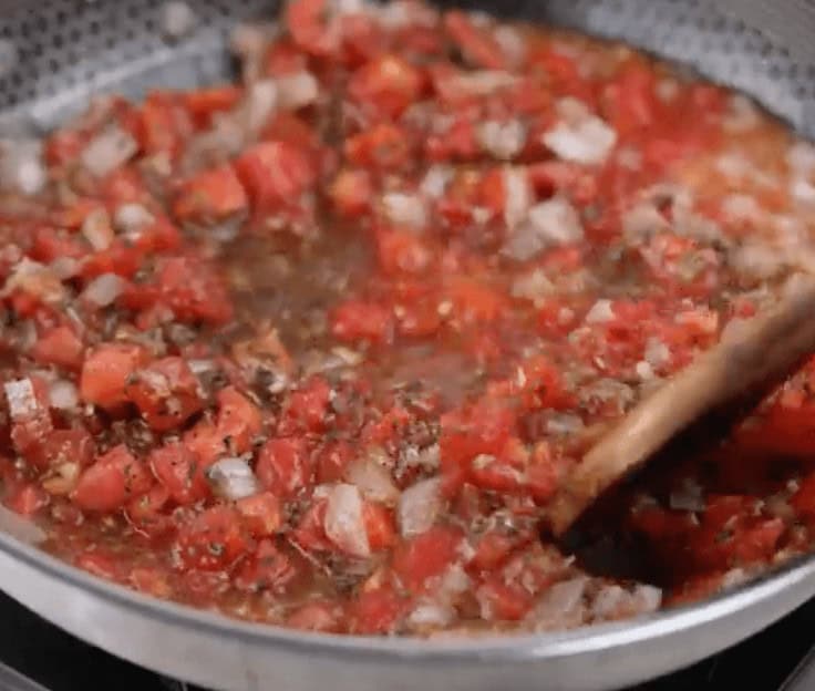 Cooking the pizza sauce in a skillet.