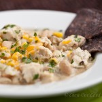 a bowl of white bean chicken chili with black tortilla chips on the side