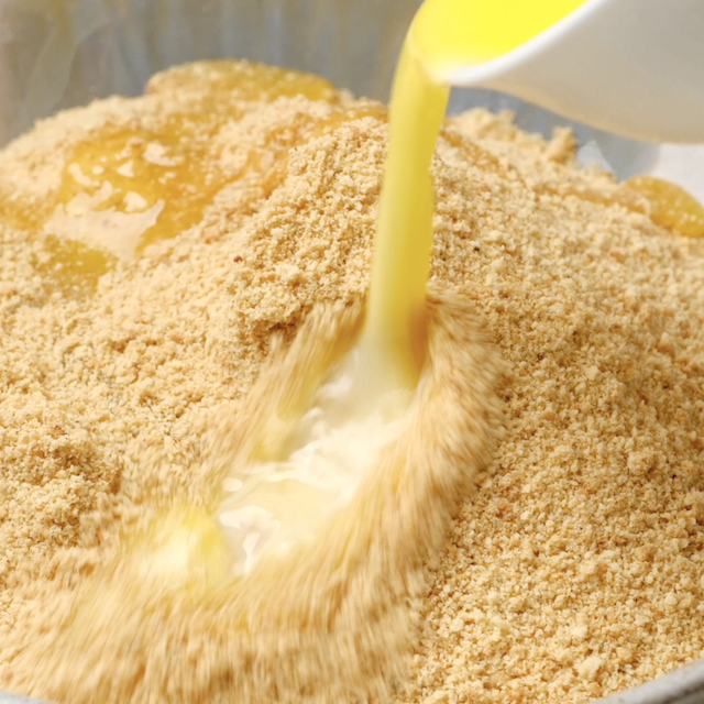Melted butter being poured into graham cracker crumbs.