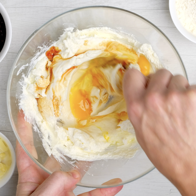 Eggs and vanilla being mixed into cheesecake layer.