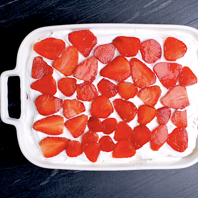 Sliced strawberries layered over cream to make strawberry icebox cake.