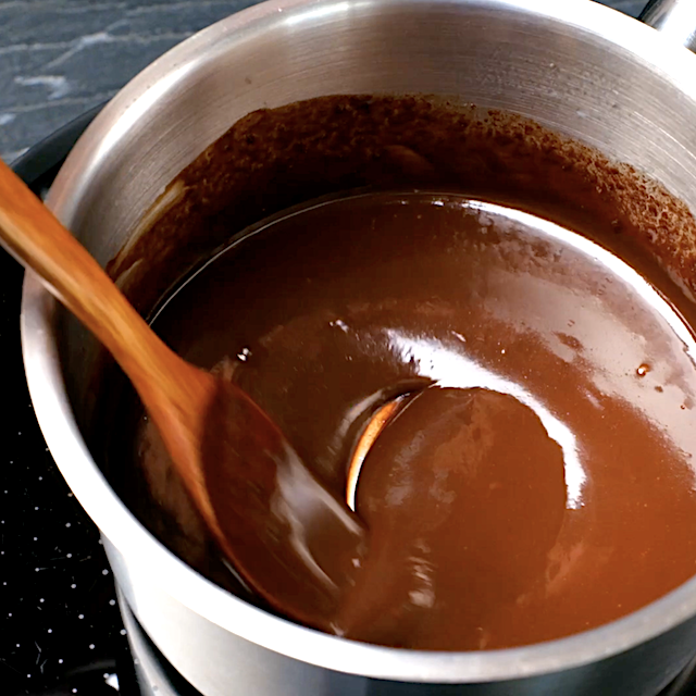 Simple chocolate ganache being made in a saucepan to drizzle over strawberry icebox cake.