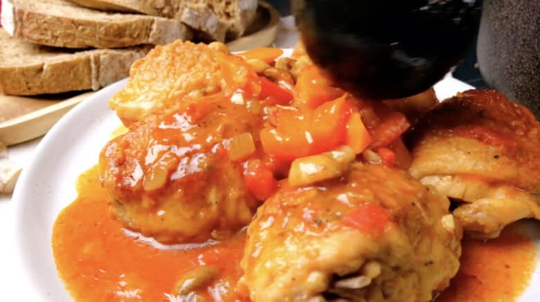 Chicken cacciatore sauce being poured over chicken.