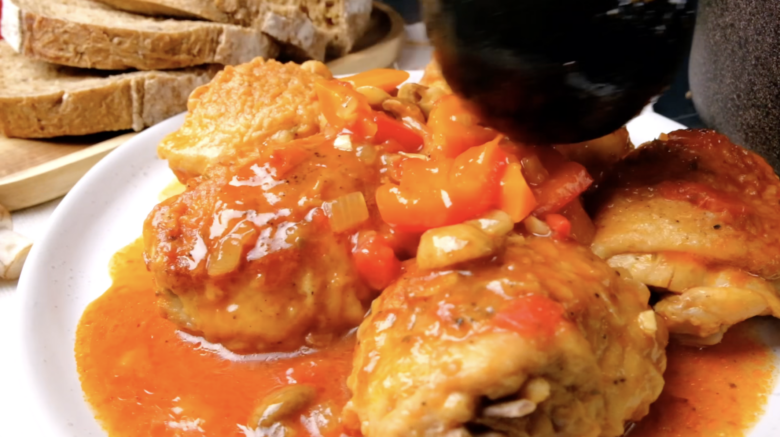 Chicken cacciatore sauce being poured over chicken. 