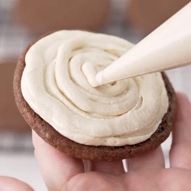 Filling being piped between cookies.
