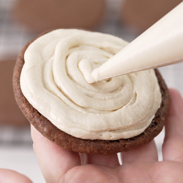 Filling being piped between cookies.