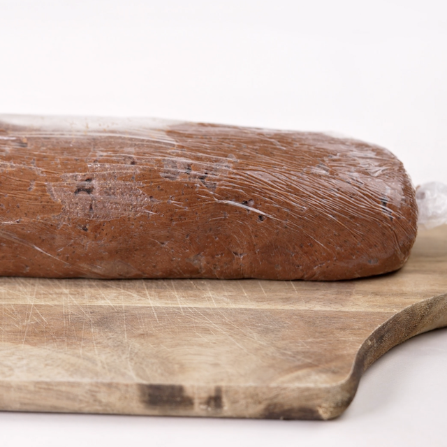 Peanut butter fudge cookie log wrapped in plastic to chill.