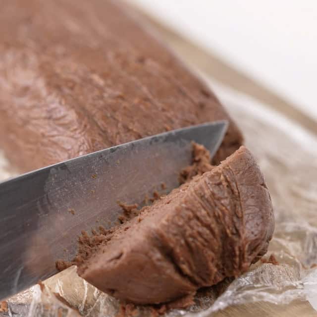 Cookie dough being sliced to make equal sized cookies.