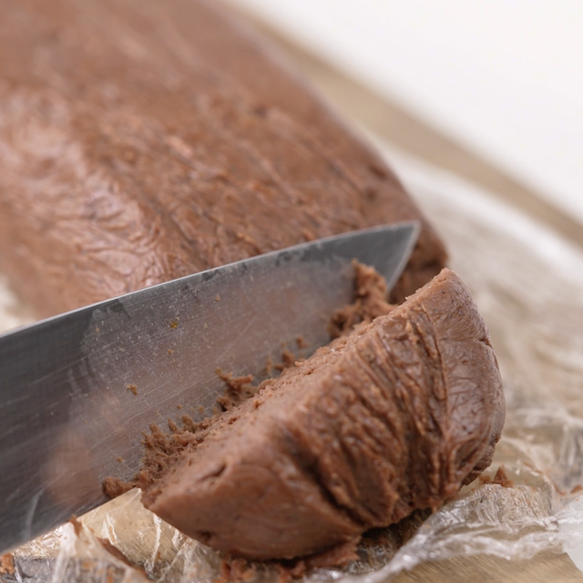 Cookie dough being sliced to make equal sized cookies.