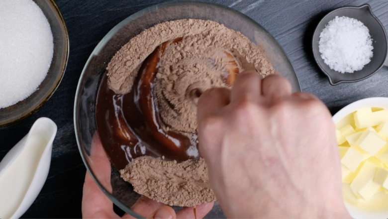 Chocolate mixture being mixed into dry ingredients to make dark chocolate brownies.