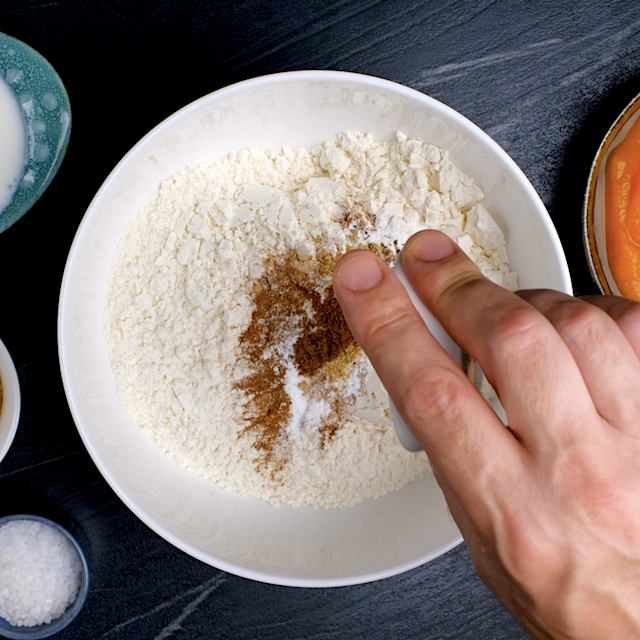 Dry ingredients to make pumpkin bundt cake being added to a mixing bowl.