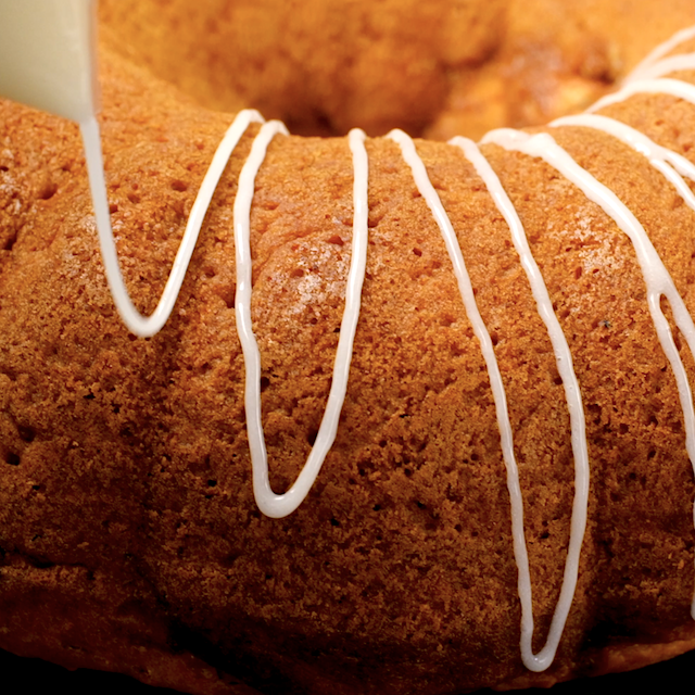 Cream cheese frosting being drizzled over pumpkin bundt cake.