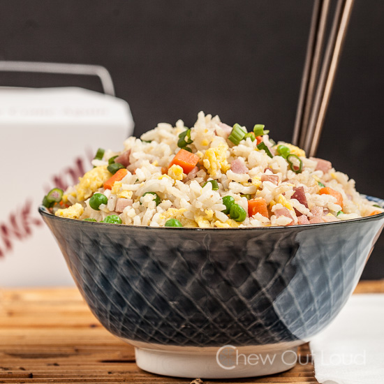 Chinese fried rice with carrots and peas in a bowl with chopsticks