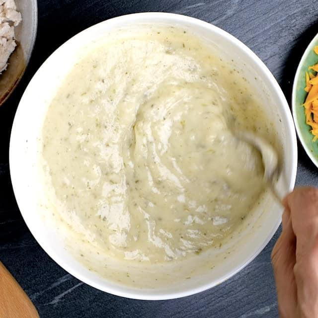 White sauce mixture being mixed together to make white chicken enchilada casserole.