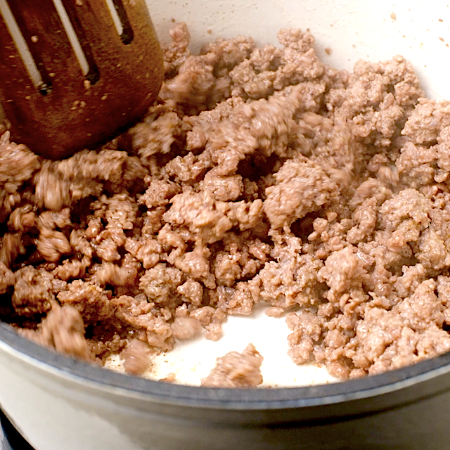 Crumbled sausage being cooked in a large pot to make zuppa toscana.
