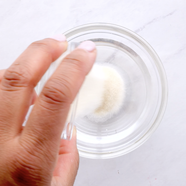 Gelatin being added to a bowl with water to make whipped cream frosting.