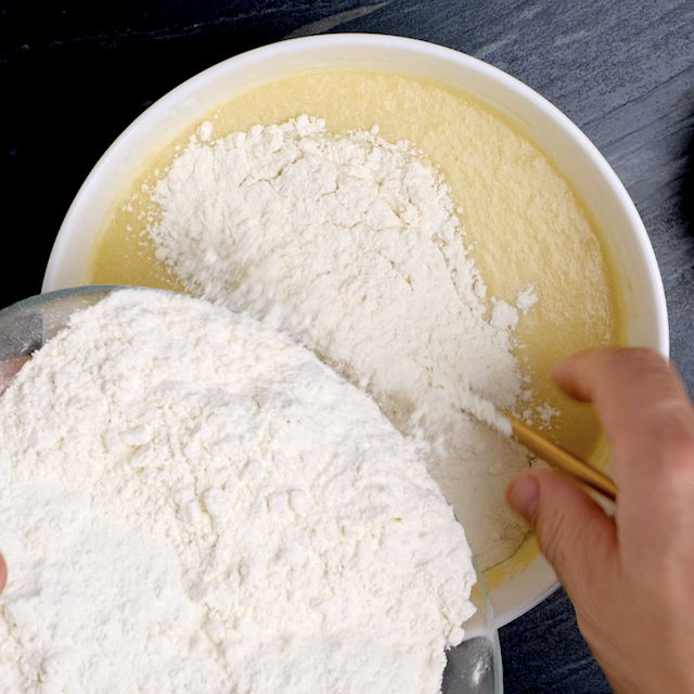 Dry ingredients being added into wet ingredients to make brown sugar bundt cake.