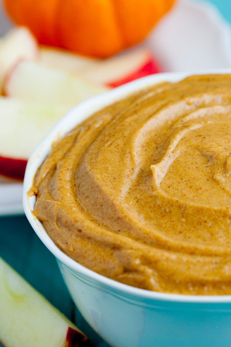 Pumpkin cream cheese dip in a bowl with apple slices.