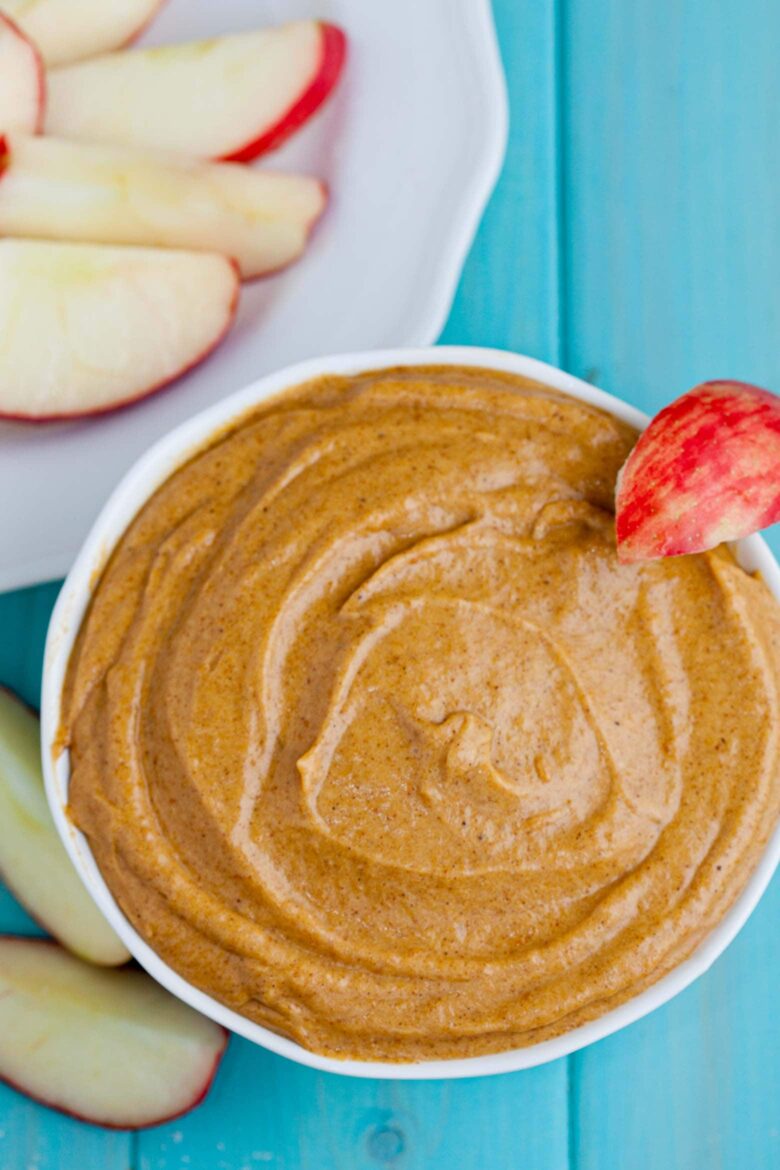 Pumpkin cream cheese dip in a bowl with apple slices.