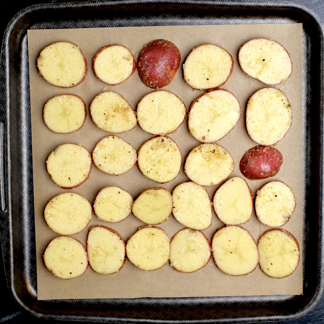 Seasoned potatoes on a baking sheet to make parmesan roasted potatoes.