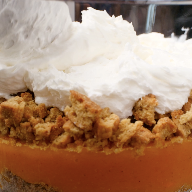 Pumpkin trifle being layered into a glass trifle bowl.