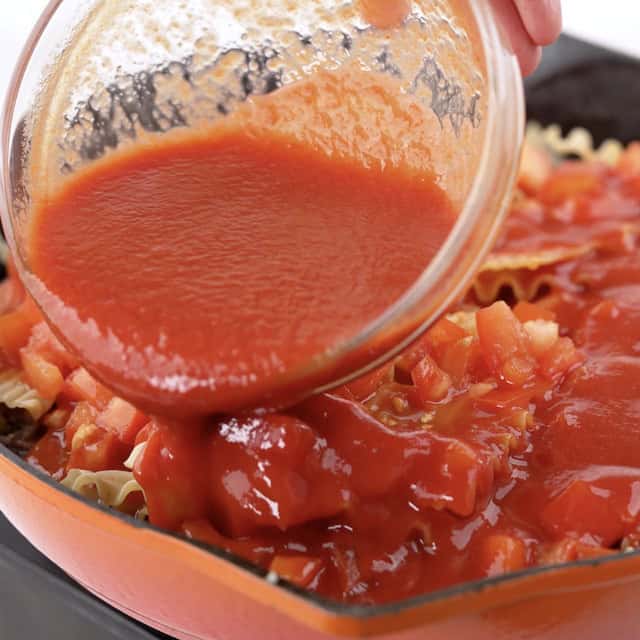 Tomato sauce being added to a pan to make skillet lasagna.