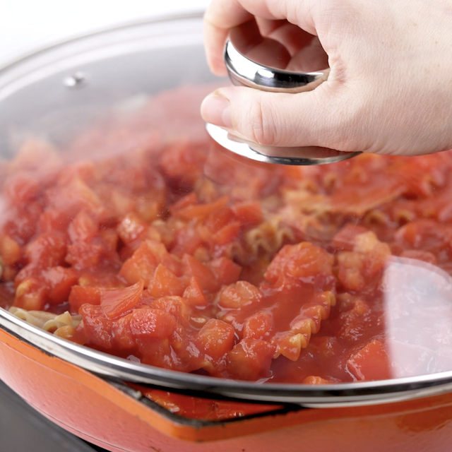 A lid being added to the skillet to make skillet lasagna.