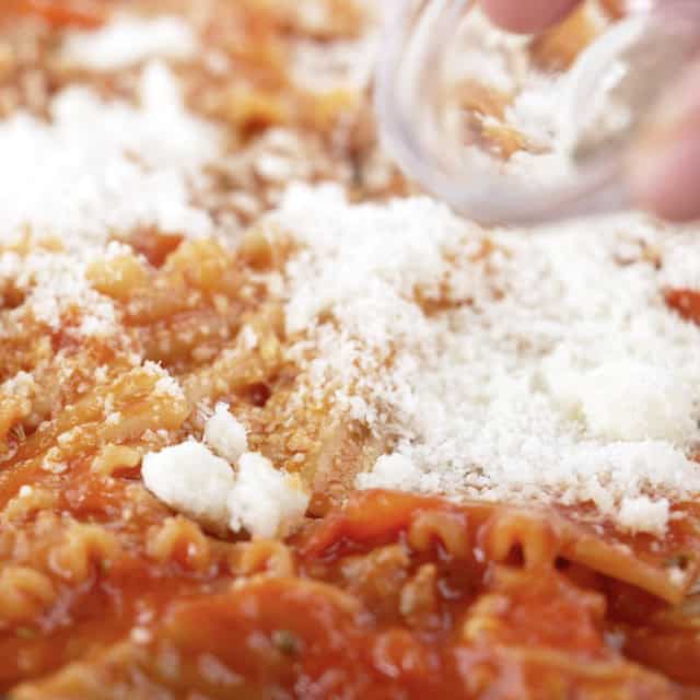 Parmesan cheese being added to a pan to make skillet lasagna.