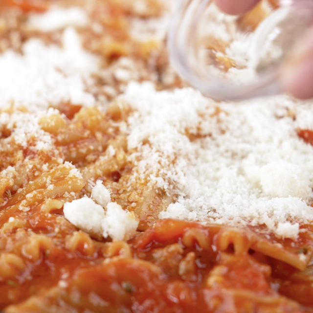 Parmesan cheese being added to a pan to make skillet lasagna.