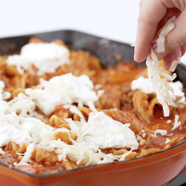 Mozzarella cheese being added to skillet lasagna.
