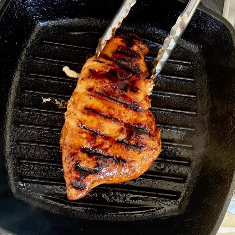 BBQ chicken grilling on cast iron grill.