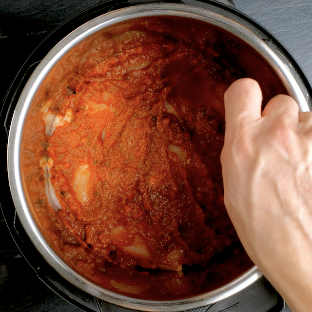 Salsa being added on top of chicken in a crockpot to make crockpot salsa chicken.