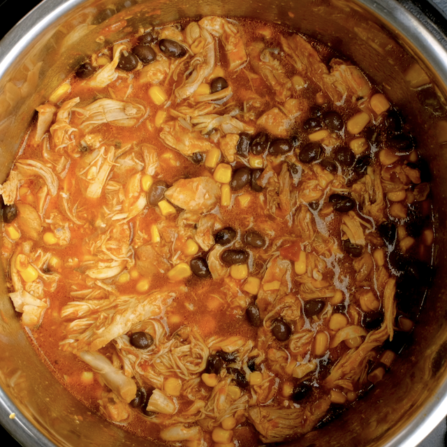 Beans and corn added to crockpot to make salsa chicken.