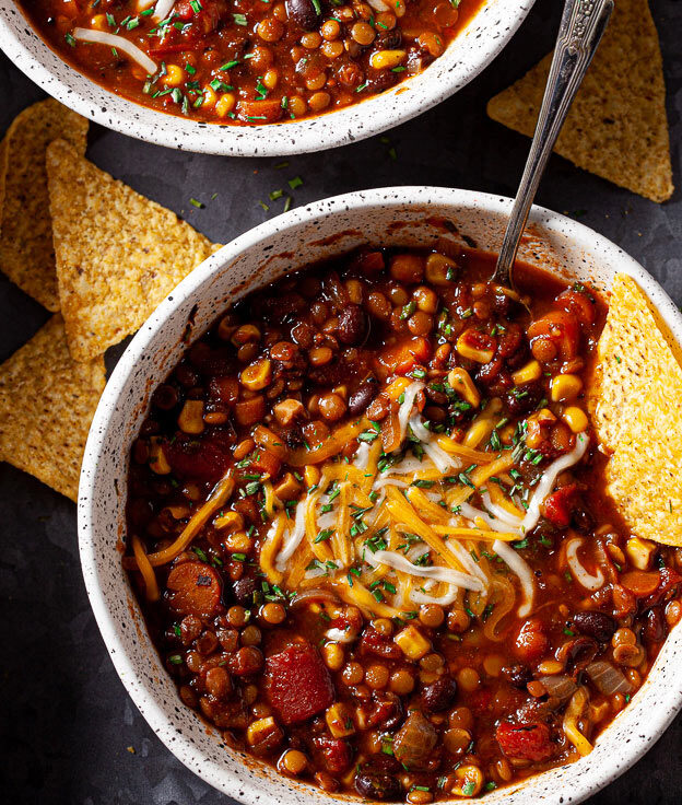 lentil chili in bowl with cheese and tortilla chips