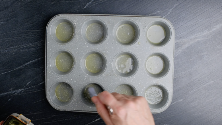 Popover tin being brushed with melted butter.