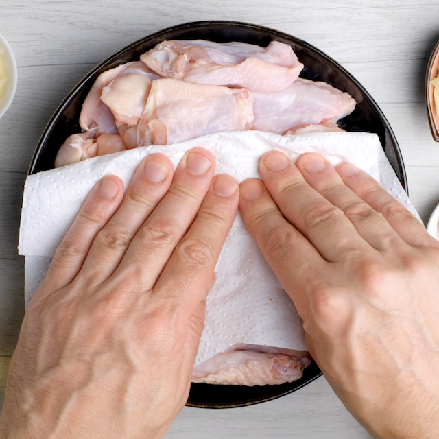 Chicken wings being patted dry to make Asian chicken wings at home.