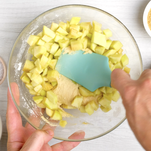 Chopped apples being folded into apple coffee cake batter.