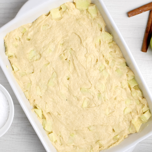 Apple coffee cake batter spread in a greased pan.