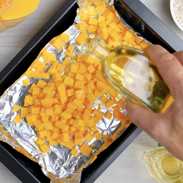 Overhead shot of butternut squash cubes on a baking sheet ready to be roasted.
