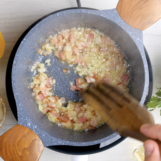 Bacon and onions being sautéed in butter to make butternut squash risotto.