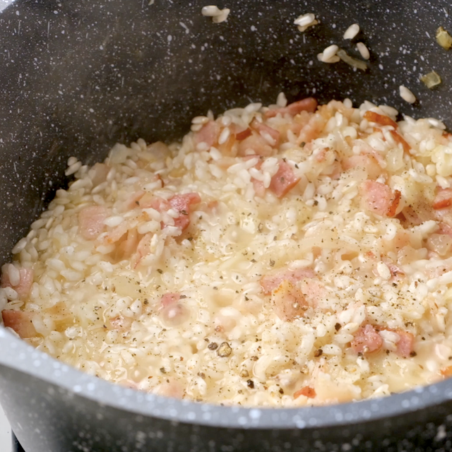 Tender and creamy risotto with bacon bits in a pot.