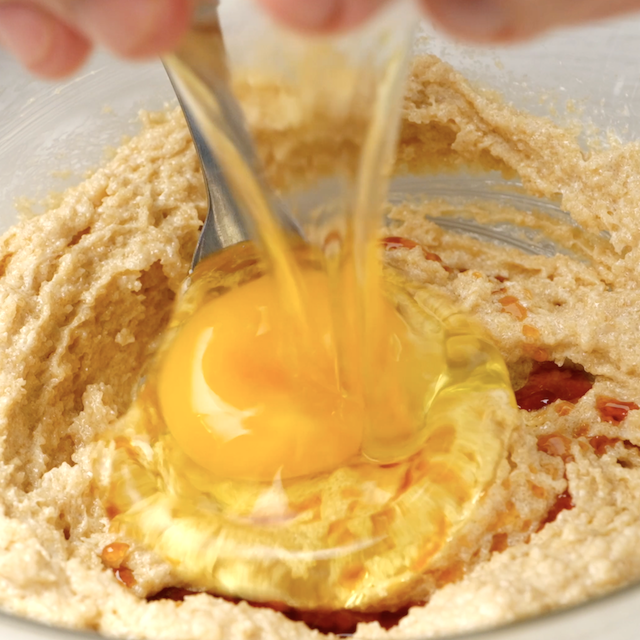 Egg being cracked into cranberry cake batter.