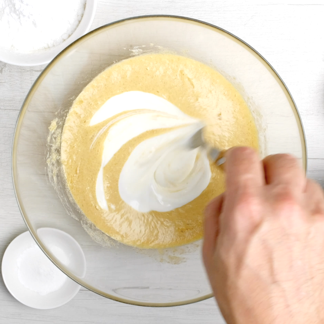 Yogurt being stirred into cranberry cake batter.
